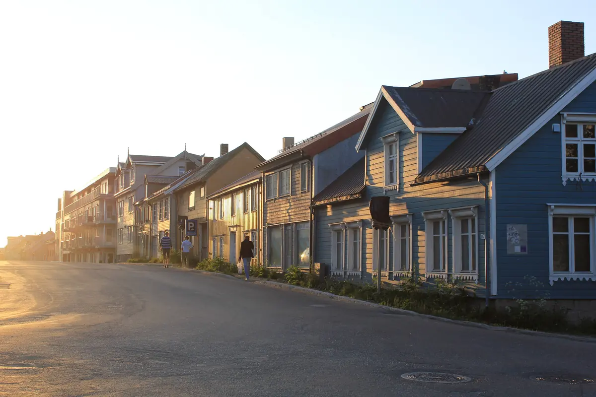 A quiet Tromsø street lined with wooden houses in low evening sun